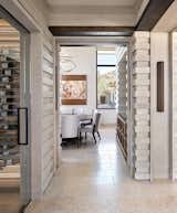 A dining room passageway is flanked by a custom wine cellar and sandblasted vein-cut stair-stepped limestone.  