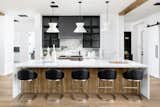 Custom rift cut white oak at the island, painted white wood on the perimeter, and black wood uppers compose this elegant and open kitchens' verticals. Horizontals are countertops of Montclair Marble (perimeter) and Thassos White Quartz (island).  