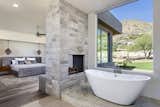 A pass-through fireplace in the master suite separates the sleeping area from teh bathroom where a freestanding tub rests on a Caesarstone platform in front of a large picture window. 
