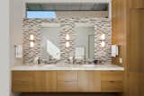 The floating vanity with dual sinks and mirrors is made of honey-colored wire-brushed oak and topped with Caesarstone. 