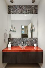 A carefully composed powder bath features a glass vessel sink and an iridescent tile backsplash. 