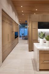 A view down the kitchen corridor to the living room reveals walls of storage behind white oak cabinetry that also holds major appliances. A quartz-topped island with a waterfall edge is one of two in the room. Flooring is honed limestone.

Project Details // Now and Zen
Renovation, Paradise Valley, Arizona
Architecture: Drewett Works
Builder: Brimley Development
Interior Designer: Ownby Design
Photographer: Dino Tonn
Millwork: Rysso Peters
Limestone (Demitasse) flooring and walls: Solstice Stone
Quartz countertops: Galleria of Stone
Windows (Arcadia): Elevation Window & Door

https://www.drewettworks.com/now-and-zen/