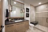 An understated palette of creams and browns is topped off in black with a quartz countertop and waterfall shower bench. LED accent lighting highlights the shower wall.

Smokey pendant lights from Troy Lighting are a perfect foil for stained oak cabinetry by Distinctive Cabinetry. 

The Village at Seven Desert Mountain—Scottsdale
Architecture: Drewett Works
Builder: Cullum Homes
Interiors: Ownby Design
Landscape: Greey | Pickett
Photographer: Dino Tonn

https://www.drewettworks.com/the-model-home-at-village-at-seven-desert-mountain/