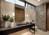 Clerestory windows draw light into this sizable powder room. For splash durability, textured limestone runs behind a custom vanity designed to look like a piece of furniture.

The Village at Seven Desert Mountain—Scottsdale
Architecture: Drewett Works
Builder: Cullum Homes
Interiors: Ownby Design
Landscape: Greey | Pickett
Photographer: Dino Tonn

https://www.drewettworks.com/the-model-home-at-village-at-seven-desert-mountain/