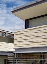 Tapered stone cladding creates a weaving effect on the façade of the house and its appearance changes throughout the day as the sun creates continuously shifting shadow patterns. 