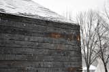Snow falls on charred wood, creating a striking contrast.