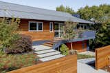 An angled view of the front of the house with new standing seam metal roof and solar panels (just out of view on the western slope).