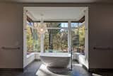 The Bentleyville Residence’s bathroom features large windows and folding doors that provide expansive views of the surrounding woodland.