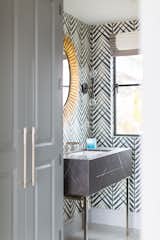 Bath Room, Marble Counter, Undermount Sink, and Porcelain Tile Floor The powder rooms were allowed extra personality. A full slab vanity is set on chrome legs, against a bamboo print wallpaper and decorative mirror.   Photo 10 of 10 in Manhattan Ave Residence by Laney LA
