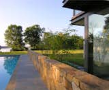The pool house is nestled around an existing stone wall that directs the view out toward the river.