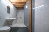 Bath Room, Concrete Counter, Wall Mount Sink, Full Shower, Wall Lighting, Open Shower, Porcelain Tile Floor, Porcelain Tile Wall, and One Piece Toilet  Photo 8 of 14 in MARTaK Passive House by Hyperlocal Workshop
