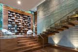 A magnificent floating staircase leads to the second story, featuring an enlarged landing that serves as a formal library with a a 15-foot high built-in bookcase.