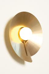 Atelier de Troupe's COMPAS sconce ($2,200) is shaped out of a single sheet of brass fastened to a simple spine. Nestled inside is a pearl of hand-blown, sandblasted glass. &nbsp;&nbsp;