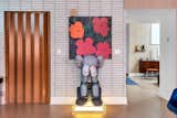 The Andy Warhol’s Flower, 1964 and KAWS’s Seated Companion sculpture in the artist’s studio cleverly represent both the beauty and frustration of creating art.
