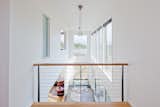 A double height hallway frames views of the pond and the heavily forested hillside while also creating lines of site between rooms and varying levels.