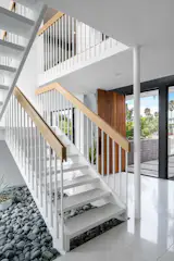 The entry foyer features a steel and terrazzo sculptural staircase in a recessed bed of river rock.