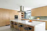 The custom kitchen’s airy feel owes to the use of beach-washed materials such as rift oak, stone and a Heath tile backsplash in a sea green tone.  The large window at the sink captures views of the rear yard and dining cabana. 