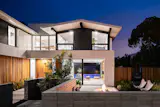 The wall-to-wall, full height sliding doors create an indoor-outdoor experience by extending the front yard fire pit and seating area through the living room to the backyard swimming pool and cabana beyond.
