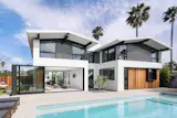 The black-framed glass wall opens up the living room and connects it to the patio that surrounds the swimming pool. The widow wall has tinted glass, and when opened, it’s held in place by an external frame that’s built into the architecture of the home.
