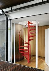 A red metal spiral staircase leads to the second-story office.