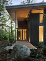 The exterior palette consists of dark cedar siding, mahogany decks, and exposed gray steel beams.&nbsp;