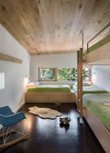 Custom, built-in bunk beds were constructed out of Baltic birch plywood, which stand out against the dark cork floors. Each bed includes a sconce for reading, along with built-in storage. In the bunk room, a sliding partition that opens to the adjacent catwalk adds a sense of whimsy.&nbsp;