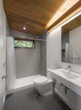 A clean, minimalist, spa-like bathroom is warmed up with a white oak ceiling and complementary lighting valence. &nbsp;