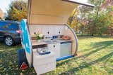 Tiny Camper's boot opens up into a mini kitchen. The teardrop’s exclusive model includes a gas stove, sink with water pump, and refrigerator.