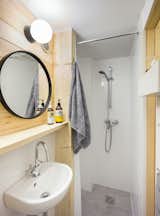 For a clean and minimal aesthetic, white and gray tiles are paired with pine wood in the bathroom.