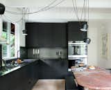 The kitchen features hacked IKEA cabinets—Brit and Daniel built custom fronts and side panels out of Valchromat, a recycled engineered wood. The cabinets are topped with black steel, which extends up the wall as backsplash. "We wanted to find an inexpensive way of doing a really terrific kitchen," says Daniel. "The metal, which is a cold-rolled sheet of blackened steel, is a unique material that will develop a patina over time, but will also be super durable—and again, very cost effective."
