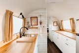 In the kitchen, birch cabinets painted in a bright white are topped with solid ash countertops.