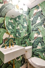 “Wallpaper came into the picture, which was totally fun,” Ron says. The new powder room is gussied up with CW Stockwell Martinique wallpaper, a Scarabeo Ceramiche Teorema wash basin, and light fixtures and a mirror from West Elm.