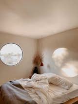 A round window casts a lunar-like glow above the bed in one of the suites.