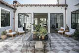 Outdoor, Tile Patio, Porch, Deck, and Large Patio, Porch, Deck Embracing California’s indoor-outdoor lifestyle, they brought the courtyard to life with encaustic Clé Tile, and architectural elements like copper gutters and steel windows. A Vesta Design table is surrounded by PK1 chairs by Poul Kjaerholm. When the doors are open, a breeze flows through the house.  Photo 9 of 13 in Windows by Charlotte Ong from The Most Shocking Before & After Renovations of 2023