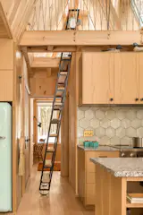 A staircase would’ve taken up too much of the precious square footage, so a ladder was installed. The ladder stores vertical and rotates outwards from the wall to create a stair-like effect with treads instead of rungs. The broom is from Village Handcraft in Wiscasset.