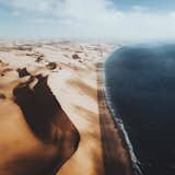 Flying high over the Namibian coast where thundering waves of the sea meet the rippling dunes of the desert Sandwich Harbour.  Photo 35 of 43 in 10 Travel Photographers to Follow on Instagram Right Now
