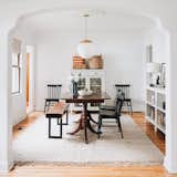 This dining room plays many roles, serving as a place for meals, crafts, mail collection, reading, and a toy/human race track. Renovator Erin Francois says "Cheers to small, multitasking homes that are typically never this clean." Here she melds high and low with a Schoolhouse Luna pendant in black and Windsor dining chairs from Target.