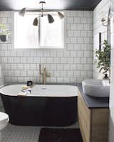 Two types of tile provide geometric texture against the inky soaking tub.