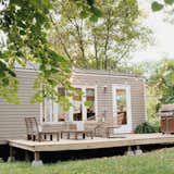Outdoor, Grass, Hanging Lighting, Back Yard, Trees, and Small Patio, Porch, Deck Their home even includes a spacious deck to bask in the sun.  Photos from 10 Tiny Home Dwellers You Should Follow on Instagram Right Now
