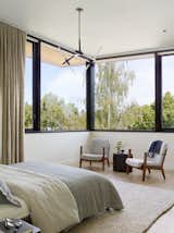Bedroom, Bed, Rug, Ceiling, Light Hardwood, and Chair The airy second floor of the home opens up to treetops all around.  Bedroom Light Hardwood Ceiling Rug Chair Photos from A Silicon Valley Retreat Sports a Butterfly Roof and Two Indoor/Outdoor Wings