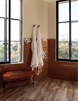 Rust-hued tile provides a pop of color against the onyx windows and bench legs. 