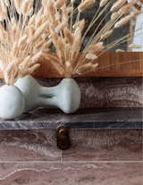A vase filled with fluffy reeds lends a bit of softness to the stone bathroom.