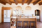 The main kitchen holds Wayfair counter stools, small dining tables and chairs, sink, faucet, and light fixtures; custom cabinetry by Café Appliances and Fire on the Mesa; and a hanging fruit basket by Xinh and Co.