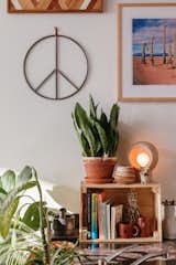 An assortment of books sits atop the kitchen counter, a nook that showcases wood art by Aleksandra Zee, a Carissa Textured Ceramic Table Lamp, and an All Roads peace sign.  Photo 7 of 13 in My House: A Creative Couple’s Live/Work Loft Is Full of Sunny, Southwestern Vibes