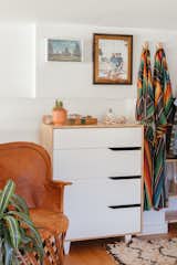 Chic desert vibes continue in the upstairs loft, where El Cosmico Kimono robes hang beside a Mexican leather chair. A custom EmmieBean portrait of the couple sits above the dresser.   Photo 10 of 13 in My House: A Creative Couple’s Live/Work Loft Is Full of Sunny, Southwestern Vibes