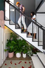 Staircase, Wood Tread, and Wood Railing In the entryway, an assortment of plants from Plants and Friends are nestled under the stairs next to an Ilano Design Rug.  Photo 18 of 18 in My House: Two Bay Area Creatives Navigate a New Normal in Their Artist Co-Op