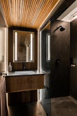 The guest house bathroom carries a moodier tone with dark wood, concrete, and black paint.