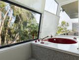 The most unique facet of the home is the red, circular soaking tub in the master bath, set against a backdrop of the city and surrounding trees.  Photo 12 of 14 in A Magnetic L.A. Midcentury Arrives on the Market for the First Time Ever at $1.95M