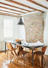 Exposed brick walls complement refinished floors in the open living, dining, and kitchen space on the ground floor. Tom applied marine epoxy, sawdust, and paint blend between the floorboards like grout before sanding them to a smooth finish.