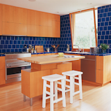 Sleek, efficient wood cabinets wrap the kitchen, which features a stunning blue tile backsplash and countertops.